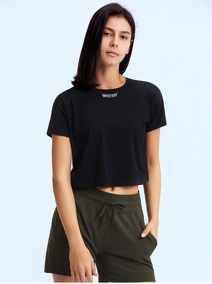Person wearing a black t-shirt with a logo and green shorts on a light blue background